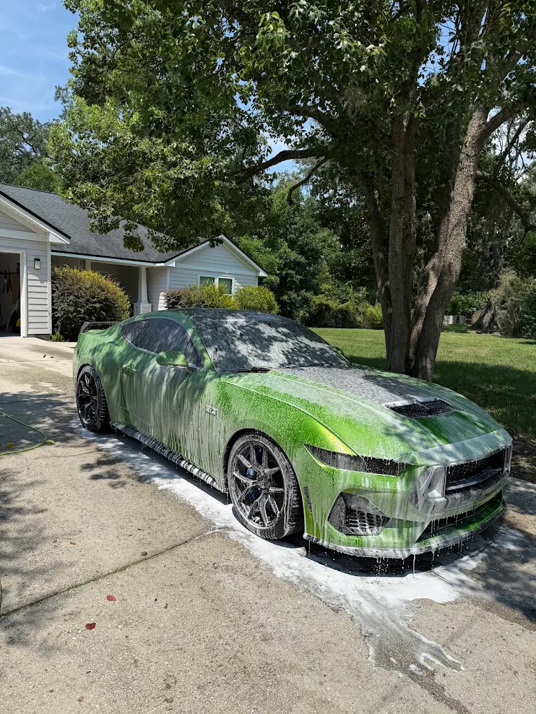 Green Ford Mustang covered in foam during a mobile detail